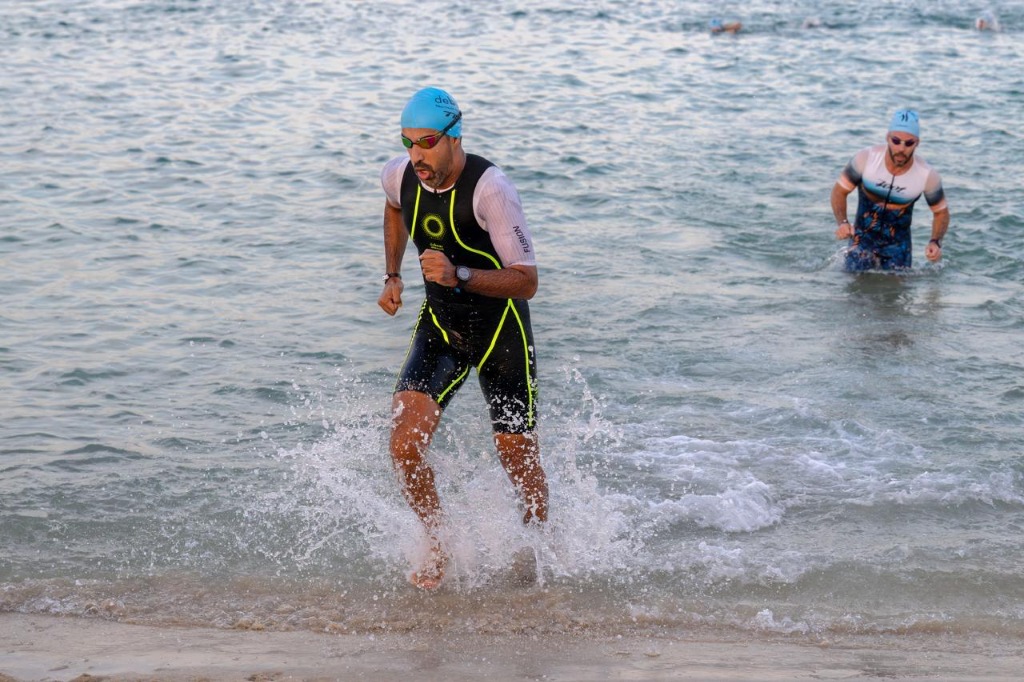 Triathletes surging out of coastal surf into transition